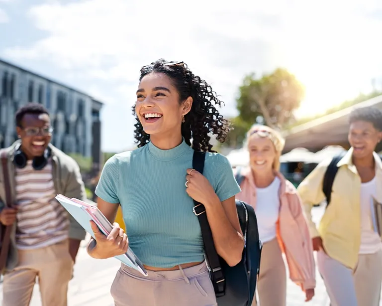Young woman smiling while walking outdoors with friends in the background.