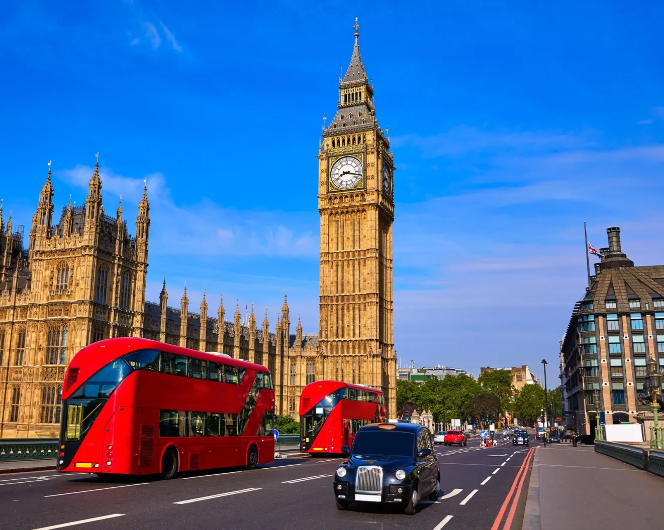 Red London buses traveling in front of Big Ben