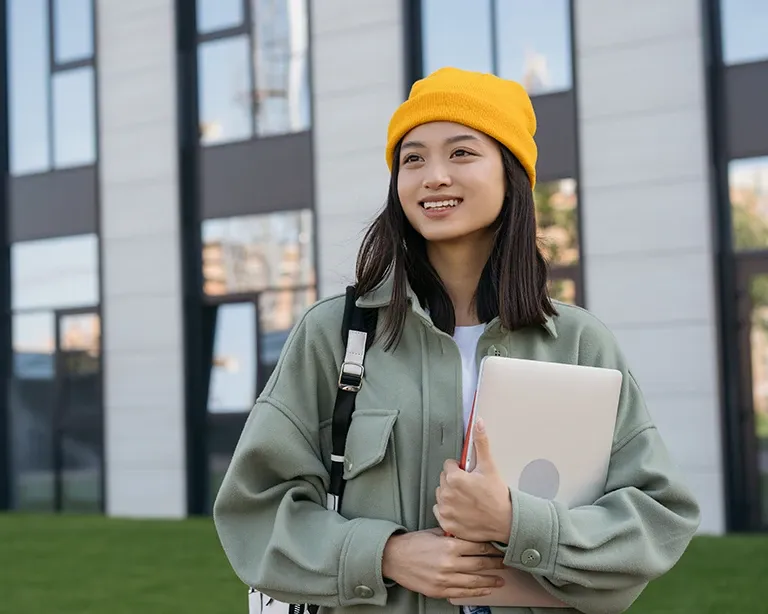 Young student with backpack holding study materials on campus
