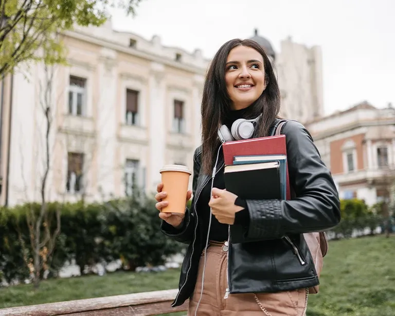 Young woman holding study materials while standing on a university campus