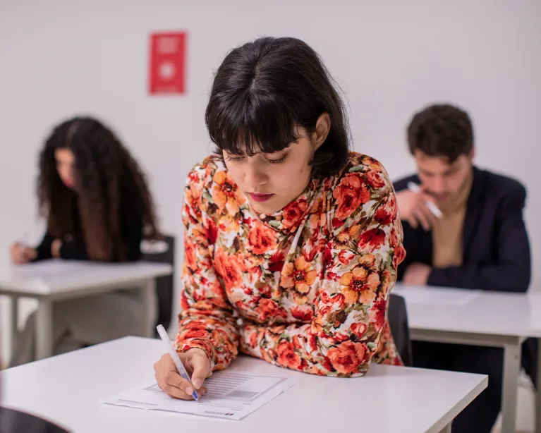 Girl writing notes and studying in a classroom during IELTS exam preparation