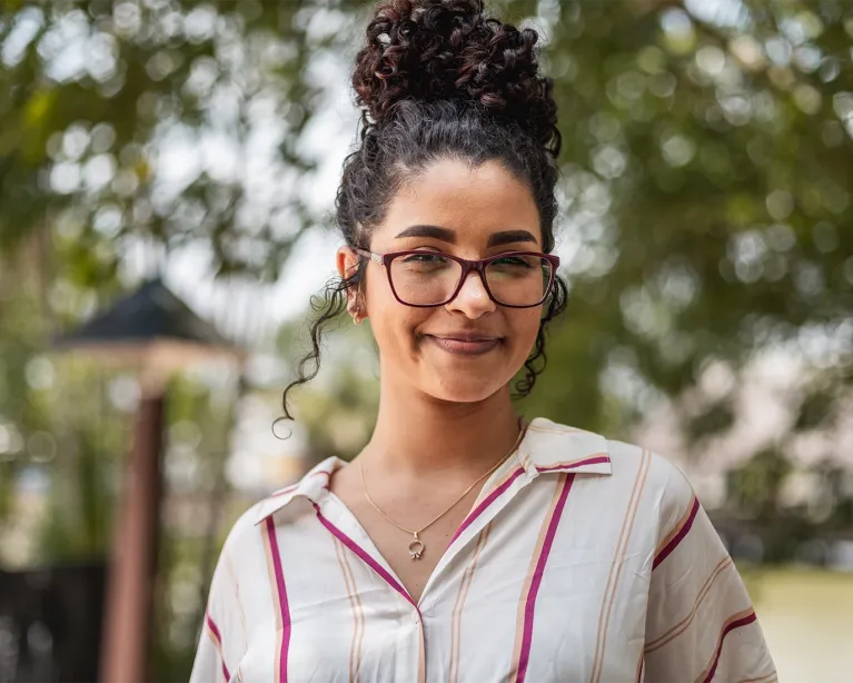 Smiling student wearing glasses standing outdoors near an IELTS test center campus