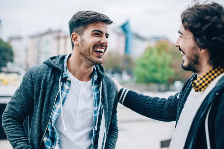 Two friends smiling and talking together outdoors.