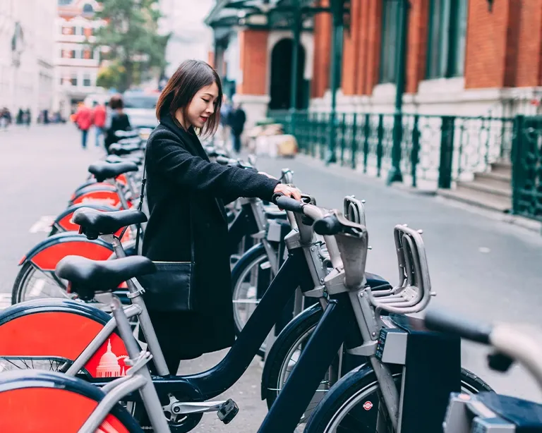 Woman standing beside rental bicycles on a city street.