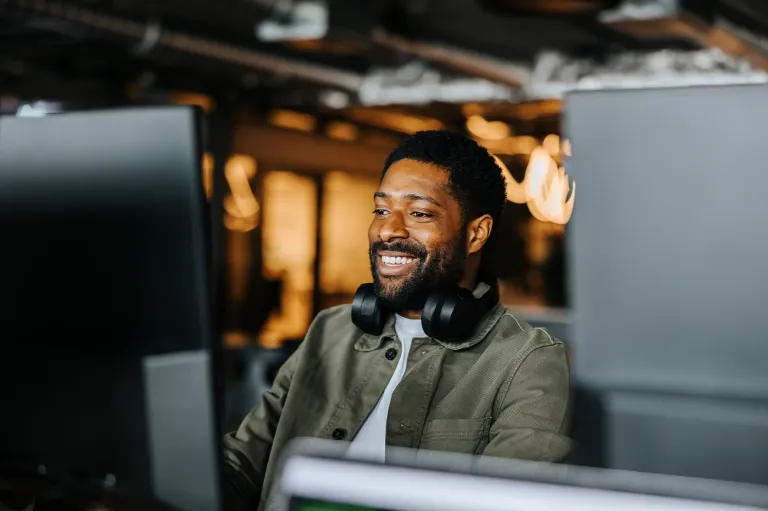 Young man wearing headphones attending an online IELTS learning session.