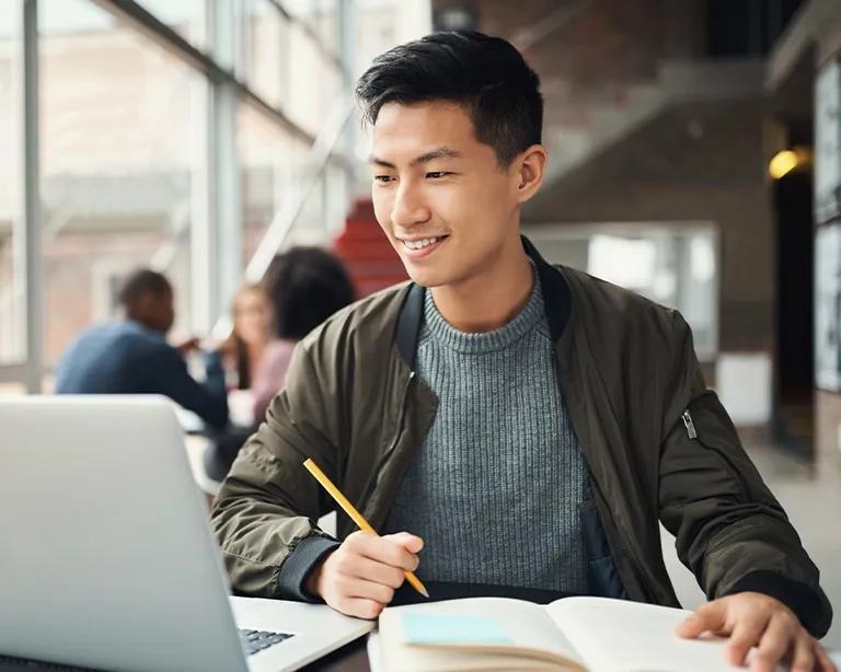 Young man studying online for the IELTS exam using a laptop.
