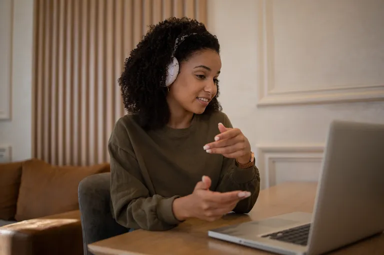 Young woman practicing for the IELTS speaking test during an online video session.