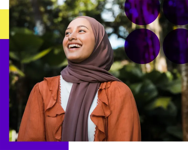 Young woman smiling while standing outdoors in a park.