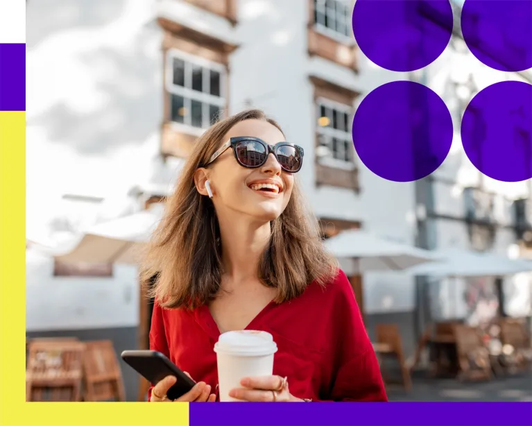 Young woman wearing sunglasses holding a coffee cup and smartphone