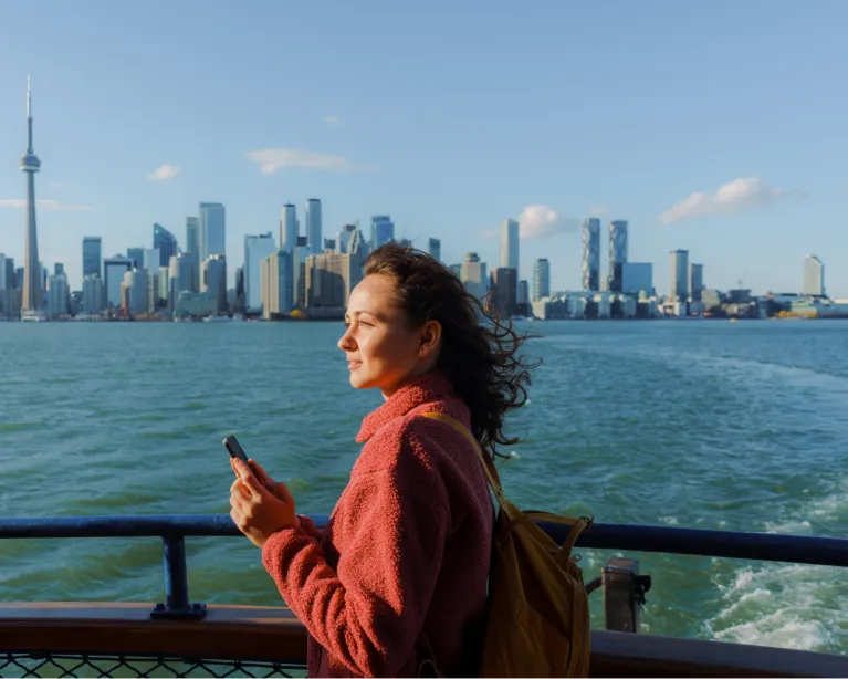 Young woman enjoying a scenic waterfront city view while traveling on a ferry.
