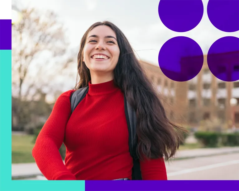 Young woman with a backpack smiling outdoors on a university campus.
