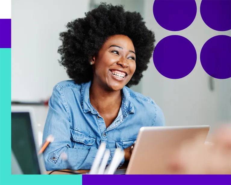 Young woman smiling while working on a laptop during a study session.