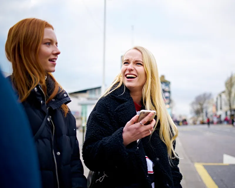 friends-chatting-outdoors-checking-mobile-phone
