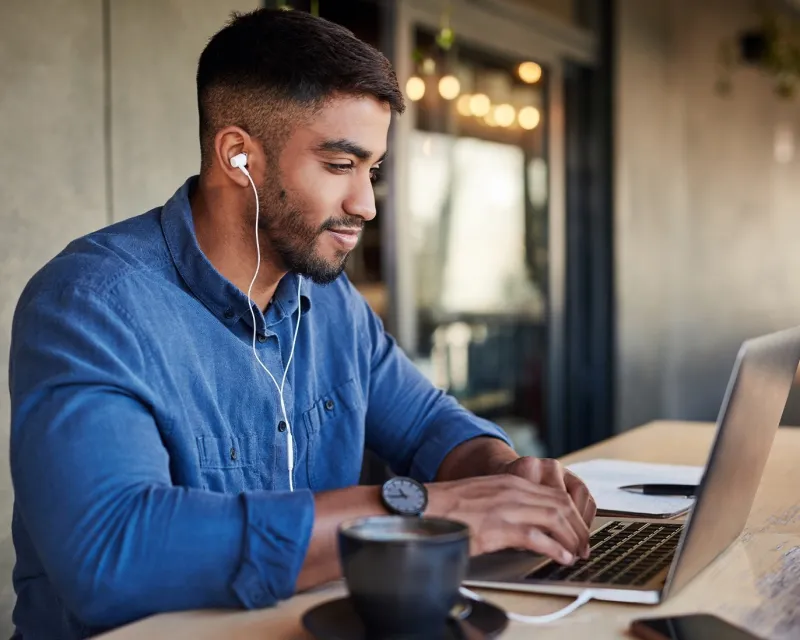 man-using-laptop-earphones-cafe