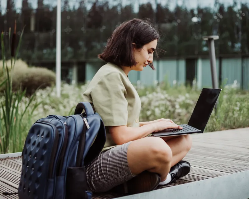 student-sitting-outdoors-campus-backpack